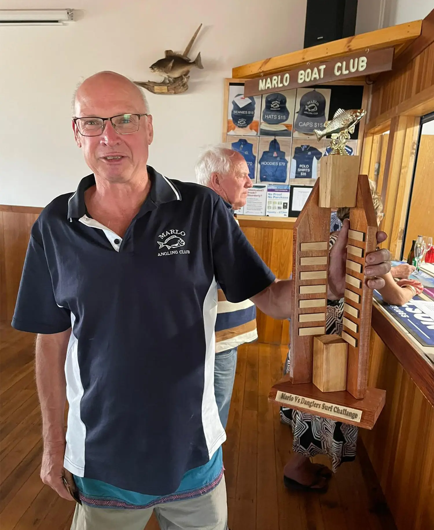 man holding a fishing challenge trophy